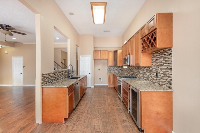 kitchen with sink, tasteful backsplash, appliances with stainless steel finishes, dark hardwood / wood-style flooring, and light stone countertops