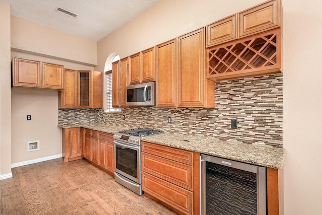 kitchen with wine cooler, light stone countertops, decorative backsplash, and stainless steel appliances