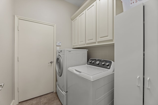 washroom with light tile patterned flooring, cabinets, and washer and dryer