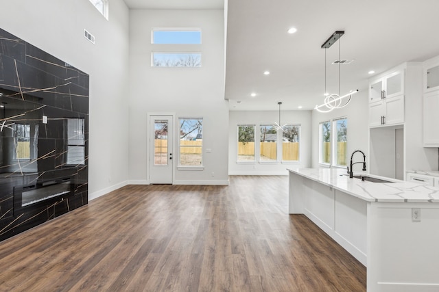 kitchen with white cabinetry, sink, decorative light fixtures, and light stone countertops