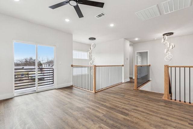 spare room with ceiling fan with notable chandelier and dark hardwood / wood-style flooring