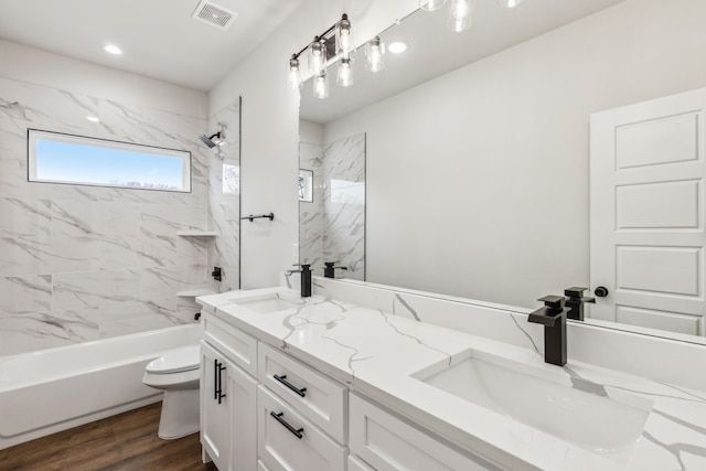 full bathroom featuring hardwood / wood-style flooring, toilet, vanity, and tiled shower / bath combo