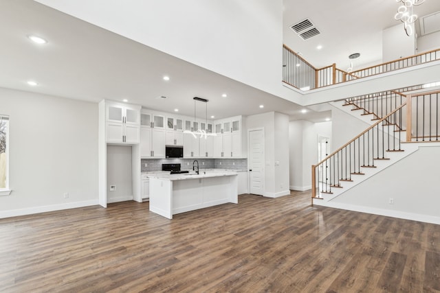 kitchen featuring white cabinetry, a center island with sink, decorative light fixtures, dark hardwood / wood-style flooring, and black electric range oven