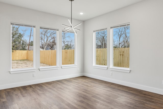 unfurnished dining area featuring an inviting chandelier, a wealth of natural light, and dark hardwood / wood-style floors