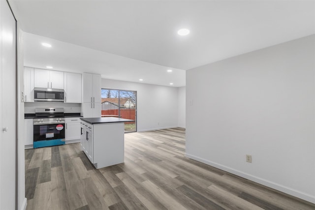 kitchen with light wood-type flooring, appliances with stainless steel finishes, white cabinetry, and a center island