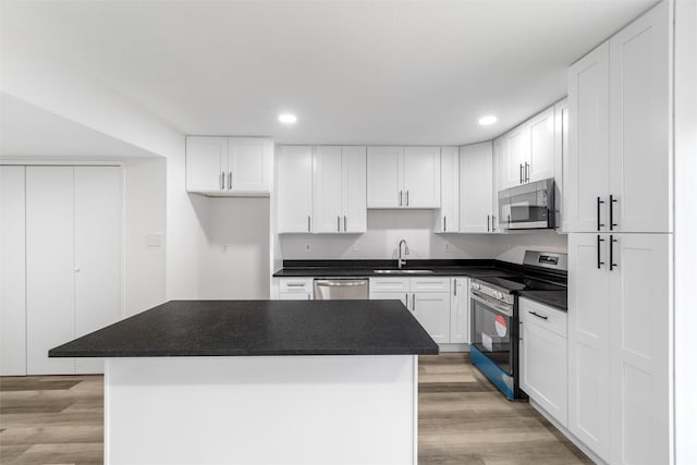 kitchen with light wood-type flooring, stainless steel appliances, white cabinets, and a center island