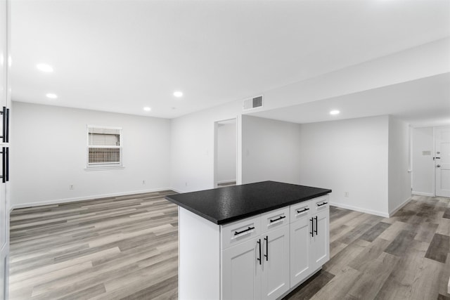 kitchen with white cabinets, a center island, and light hardwood / wood-style floors