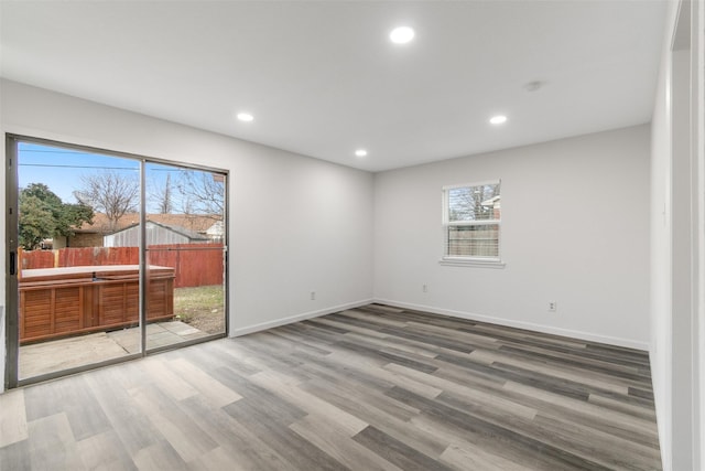 spare room with baseboards, wood finished floors, and recessed lighting