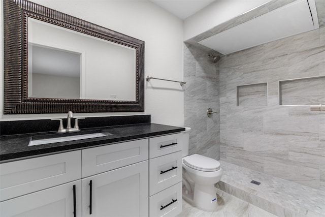 bathroom with toilet, tiled shower, and vanity