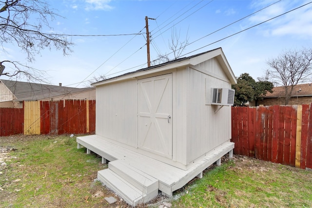 view of outdoor structure with an AC wall unit and a lawn