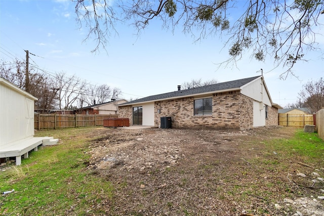 back of property featuring a lawn and central air condition unit