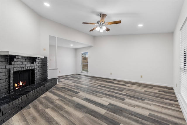 living room with hardwood / wood-style flooring, a brick fireplace, and ceiling fan