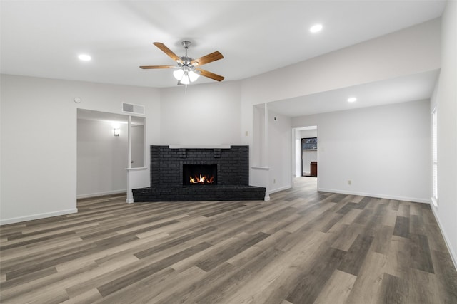 unfurnished living room featuring ceiling fan, a brick fireplace, lofted ceiling, and wood-type flooring