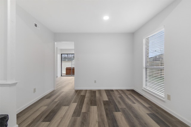 spare room featuring a healthy amount of sunlight and dark hardwood / wood-style floors