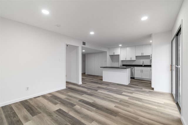 kitchen with a center island, white cabinets, stainless steel dishwasher, light hardwood / wood-style flooring, and sink