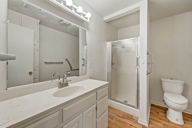 bathroom with hardwood / wood-style floors, toilet, a shower with shower door, and vanity