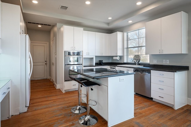 kitchen featuring white cabinets, a center island, light hardwood / wood-style flooring, and stainless steel appliances