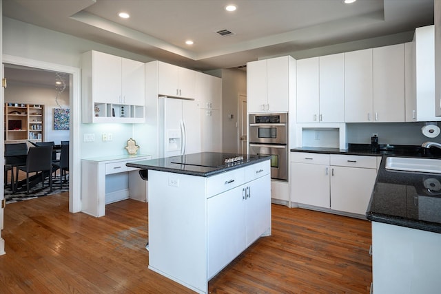 kitchen with a kitchen island, dark wood-type flooring, white cabinetry, double oven, and sink