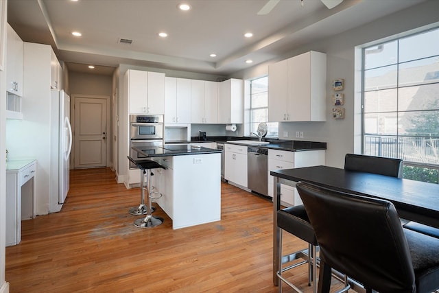 kitchen featuring plenty of natural light, white cabinetry, a center island, and stainless steel appliances