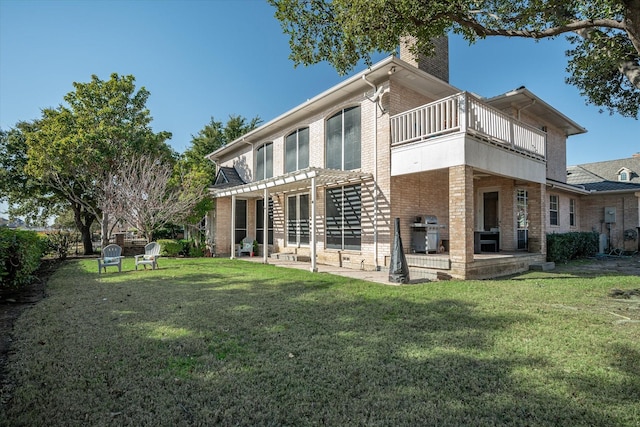 back of house featuring a balcony, a patio area, and a lawn