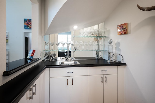 bar featuring sink, white cabinets, and vaulted ceiling