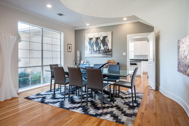 dining area featuring light wood-type flooring, a wealth of natural light, and ornamental molding