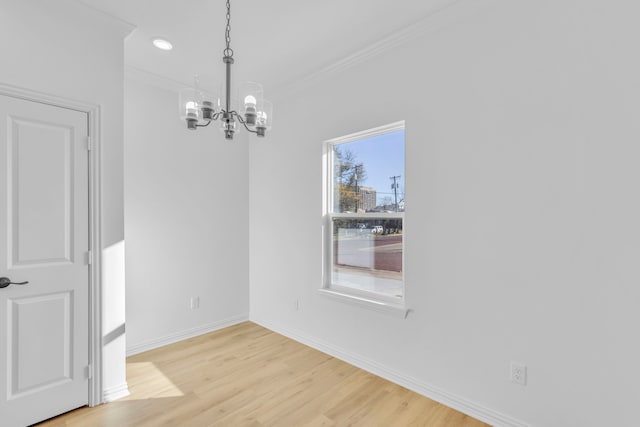 unfurnished dining area with crown molding, light wood-type flooring, and a chandelier