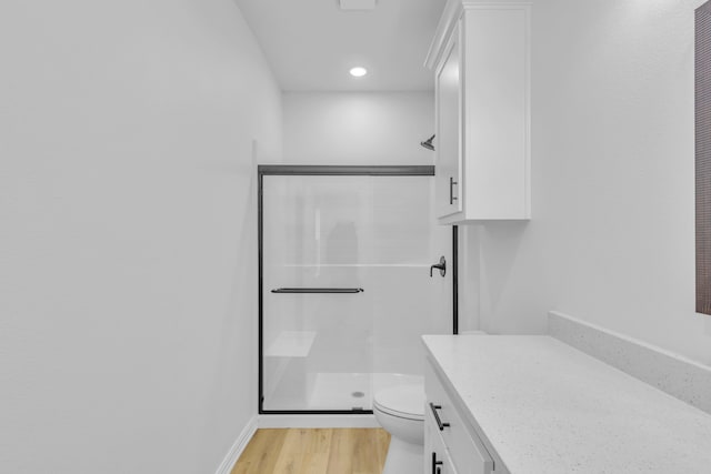 bathroom with vanity, toilet, a shower with door, and wood-type flooring