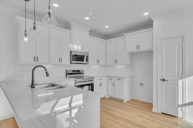 kitchen with decorative light fixtures, sink, white cabinetry, and appliances with stainless steel finishes