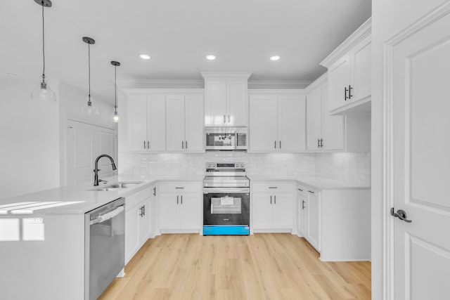 kitchen with appliances with stainless steel finishes, tasteful backsplash, white cabinets, decorative light fixtures, and sink