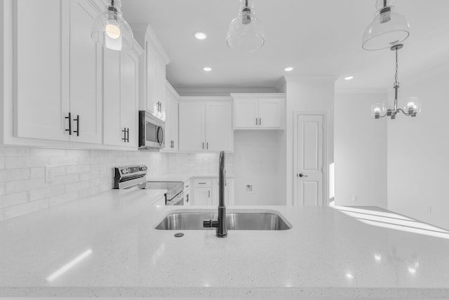 kitchen featuring pendant lighting, appliances with stainless steel finishes, sink, white cabinetry, and decorative backsplash