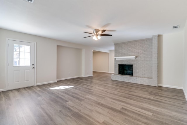 unfurnished living room featuring ceiling fan, a brick fireplace, and light hardwood / wood-style floors