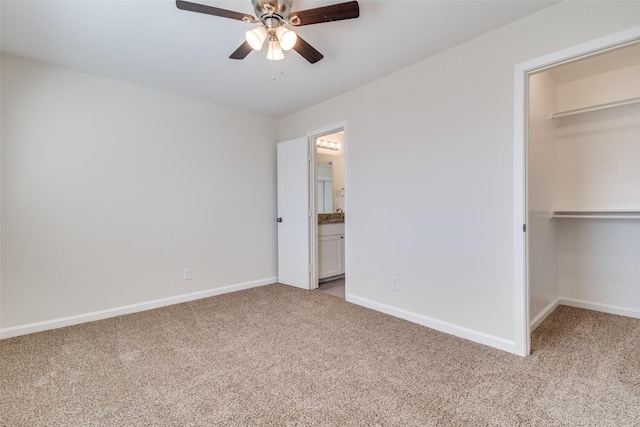 unfurnished bedroom with a spacious closet, light carpet, a closet, ceiling fan, and connected bathroom