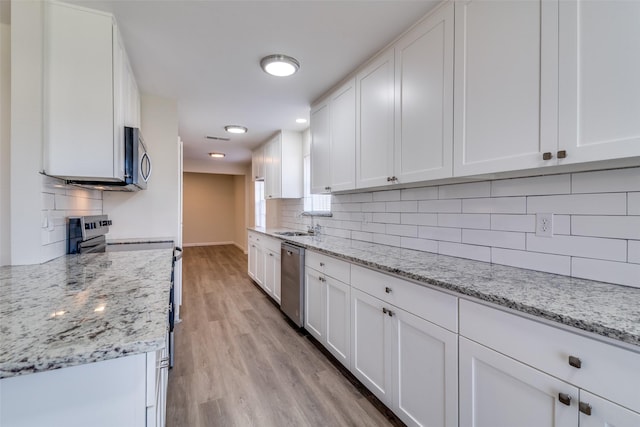 kitchen with light stone counters, sink, white cabinets, and appliances with stainless steel finishes