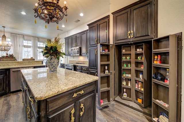 kitchen with appliances with stainless steel finishes, decorative light fixtures, dark brown cabinetry, dark wood-type flooring, and an inviting chandelier