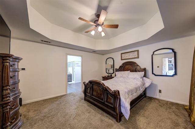 carpeted bedroom with ceiling fan and a tray ceiling