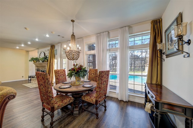 dining space with an inviting chandelier, a healthy amount of sunlight, and dark hardwood / wood-style flooring