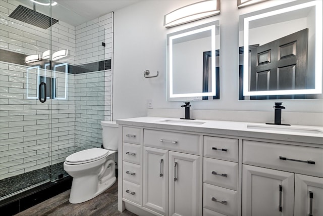 bathroom with hardwood / wood-style floors, toilet, vanity, and an enclosed shower