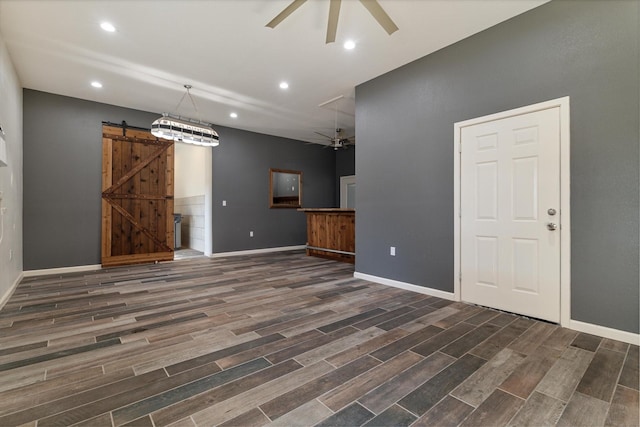 unfurnished living room with ceiling fan and a barn door