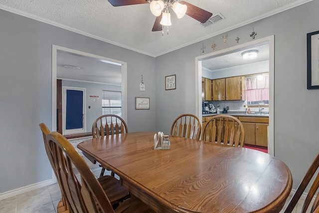 dining area featuring crown molding, ceiling fan, sink, light tile patterned floors, and a textured ceiling