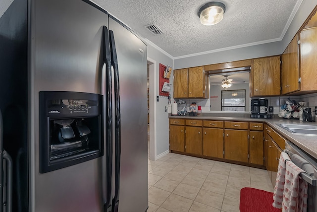 kitchen with light tile patterned floors, a textured ceiling, appliances with stainless steel finishes, and ornamental molding