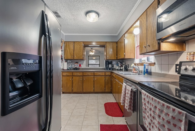 kitchen featuring a textured ceiling, stainless steel appliances, sink, backsplash, and crown molding