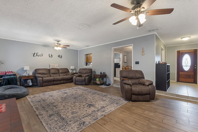 living room with ceiling fan, crown molding, light hardwood / wood-style floors, and a textured ceiling