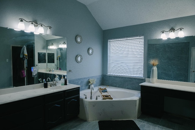 bathroom featuring tile patterned flooring, vaulted ceiling, a tub, a textured ceiling, and vanity