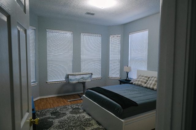 bedroom featuring a textured ceiling and dark hardwood / wood-style flooring