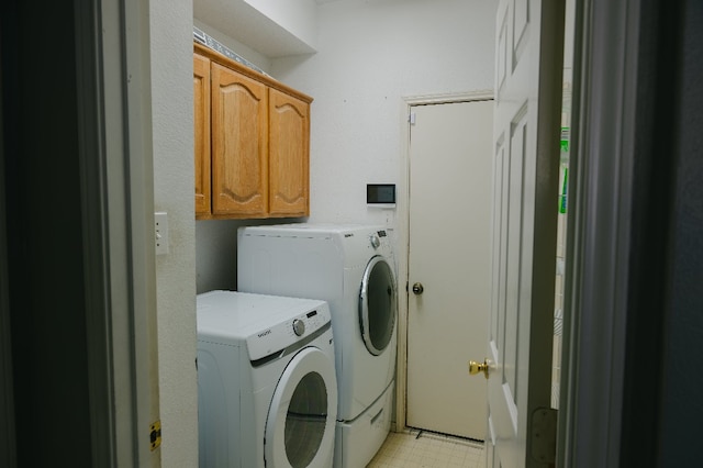 laundry room featuring washing machine and clothes dryer and cabinets