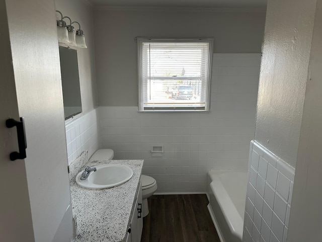 bathroom with wood-type flooring, vanity, a tub, tile walls, and toilet