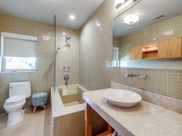 bathroom with tile walls, tile patterned floors, a tile shower, and toilet