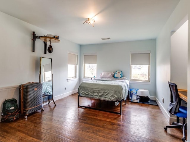 bedroom with dark hardwood / wood-style floors and multiple windows