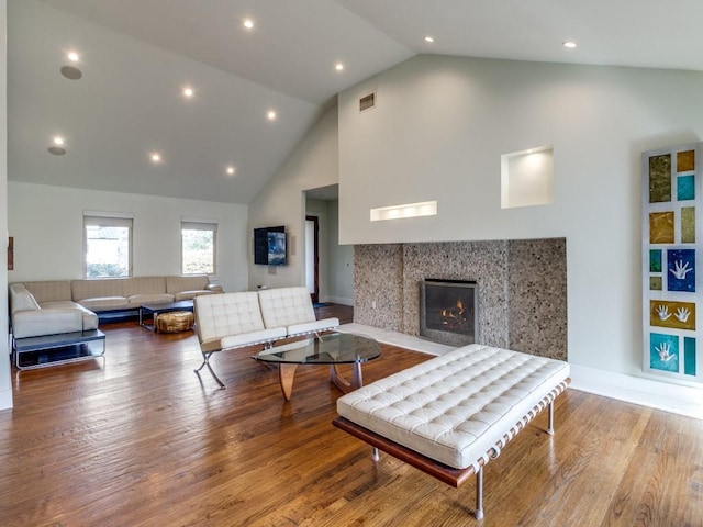 living room with hardwood / wood-style flooring, high vaulted ceiling, and a fireplace